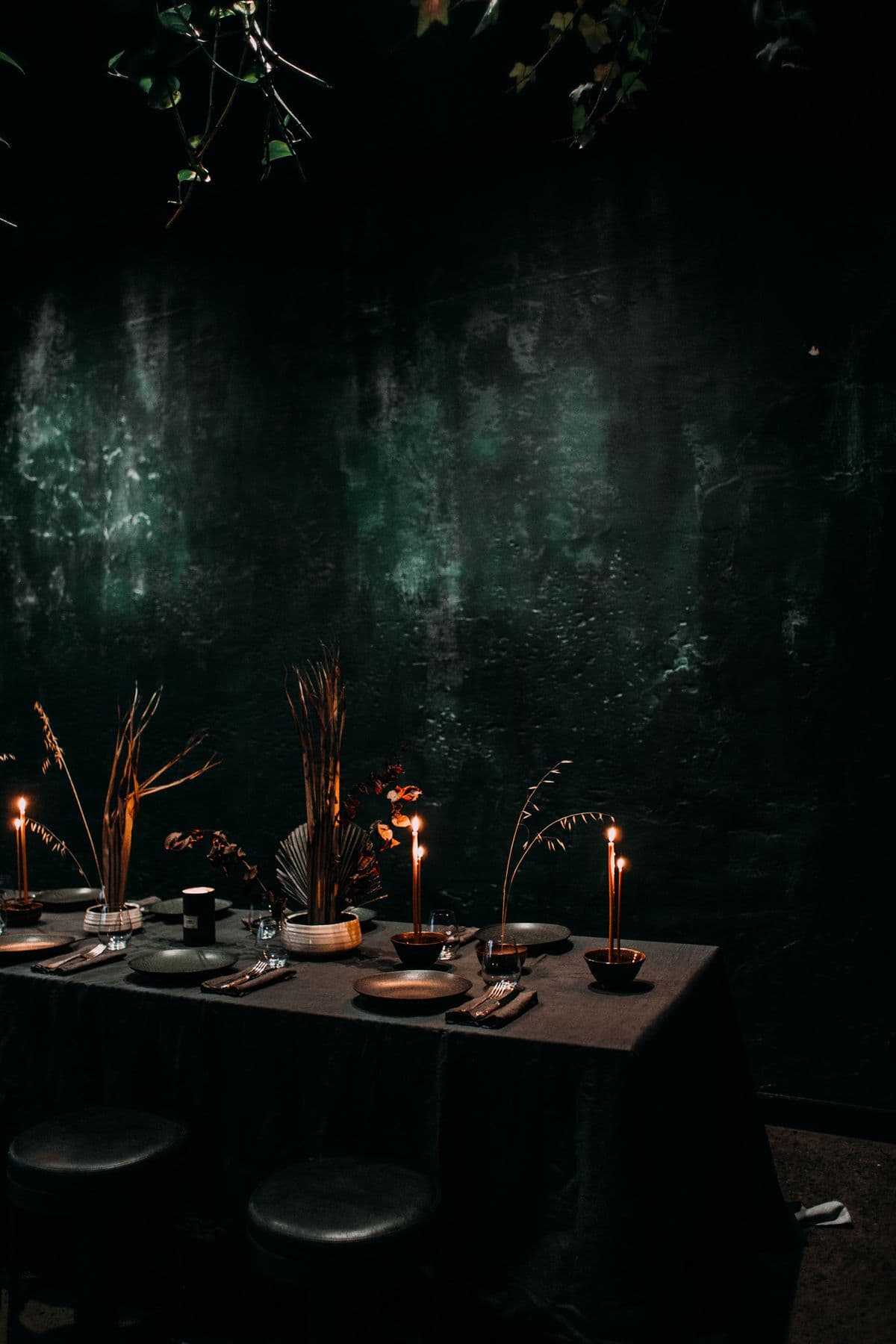 Refined event table with dark linens, candlelight, and place settings.